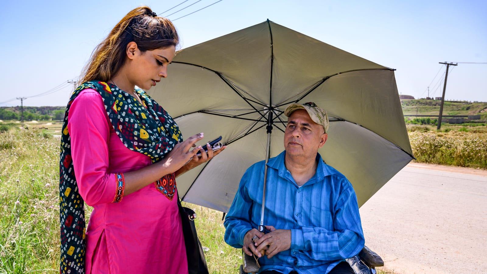 Photo of a man in a wheelchair answering the survey questions of a female healthcare worker.